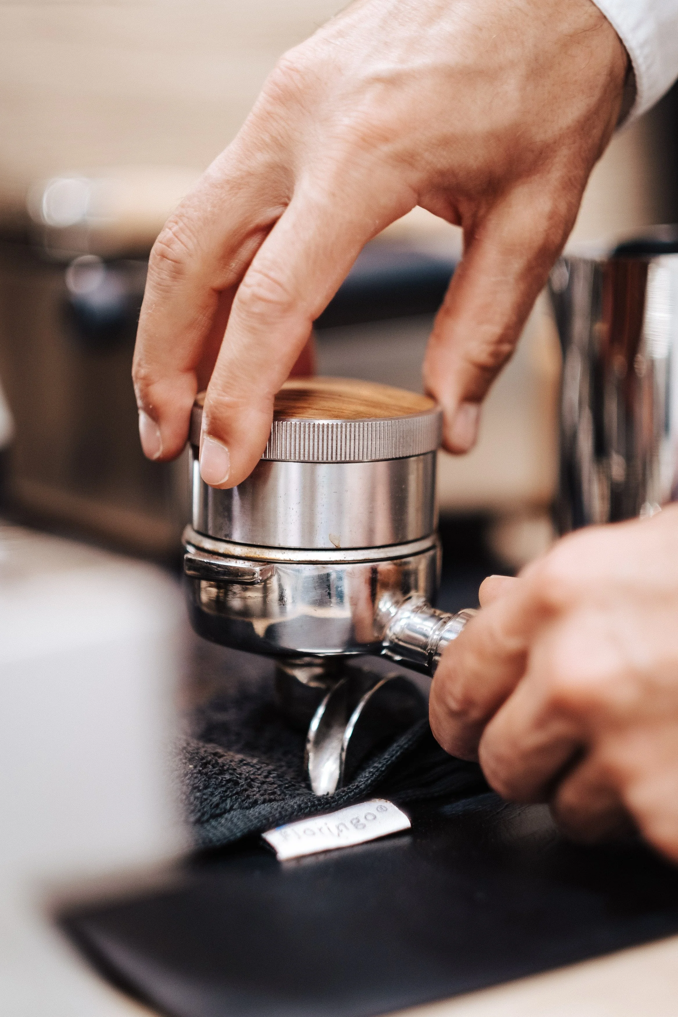 Nahaufnahme einer Hand, die eine Kaffeemühle bedient, während Kaffee gemahlen wird.