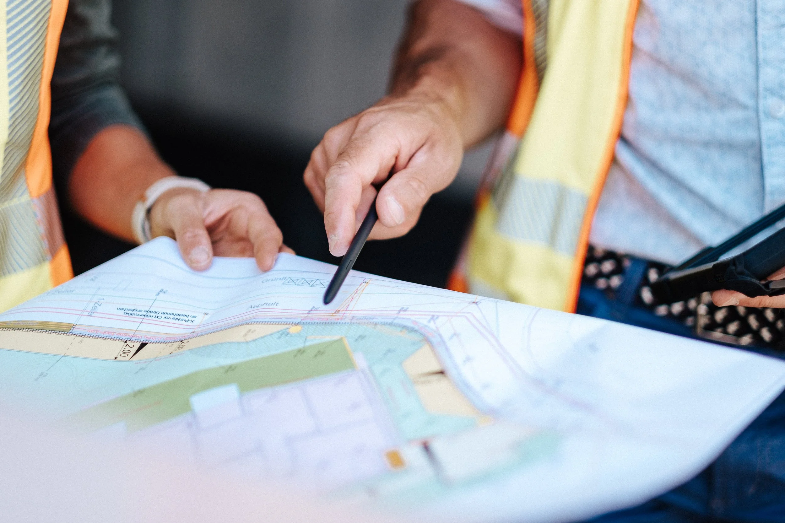 Zwei Bauingenieure oder Architekten prüfen einen Bauplan oder eine Karte, während sie auf einer Baustelle oder in einem Baugebiet stehen.