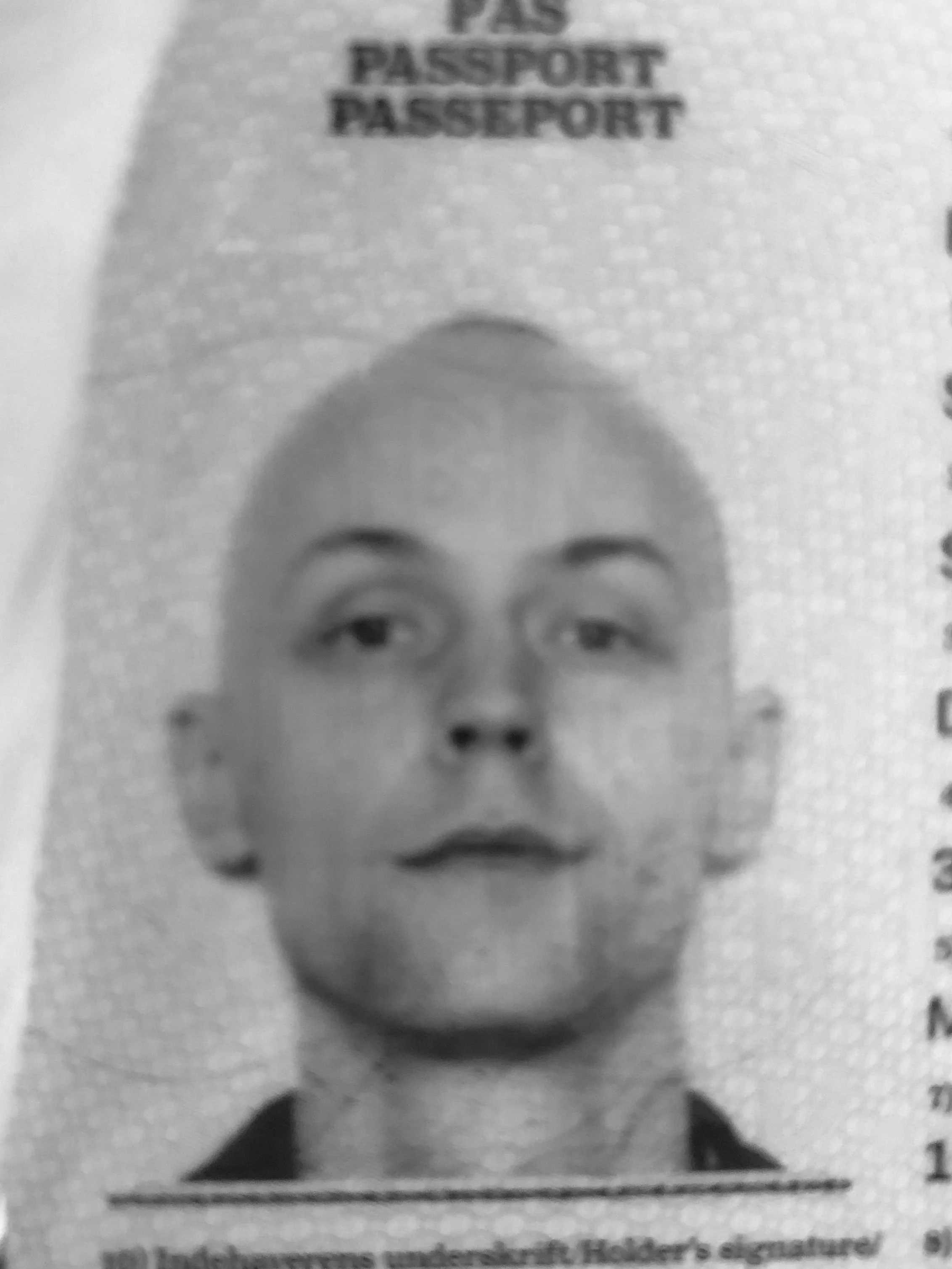 Black and white close-up of a passport photo showing a person's face with the word 'PASSPORT' visible.