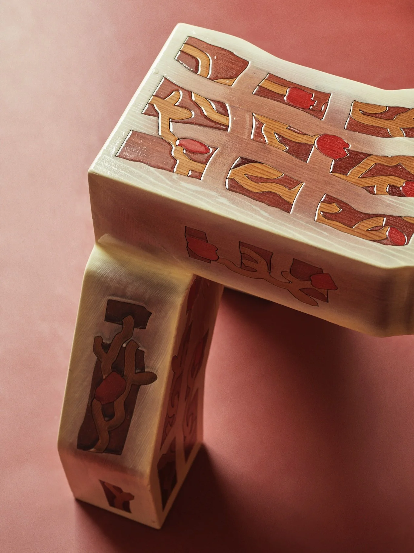 Decorative ceramic stool with geometric patterns on a red background.