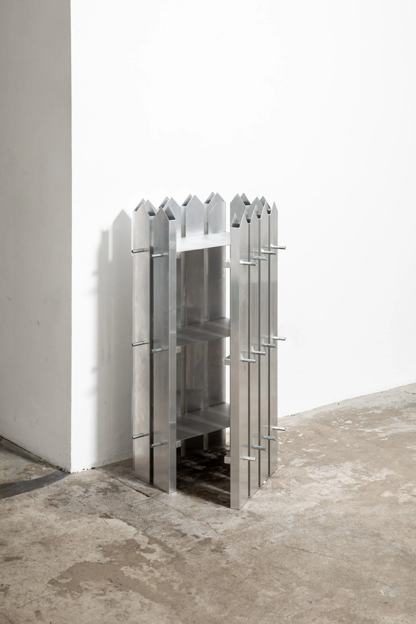 Metallic shelving unit with vertical slats and peg accents inside an indoor corner setting.