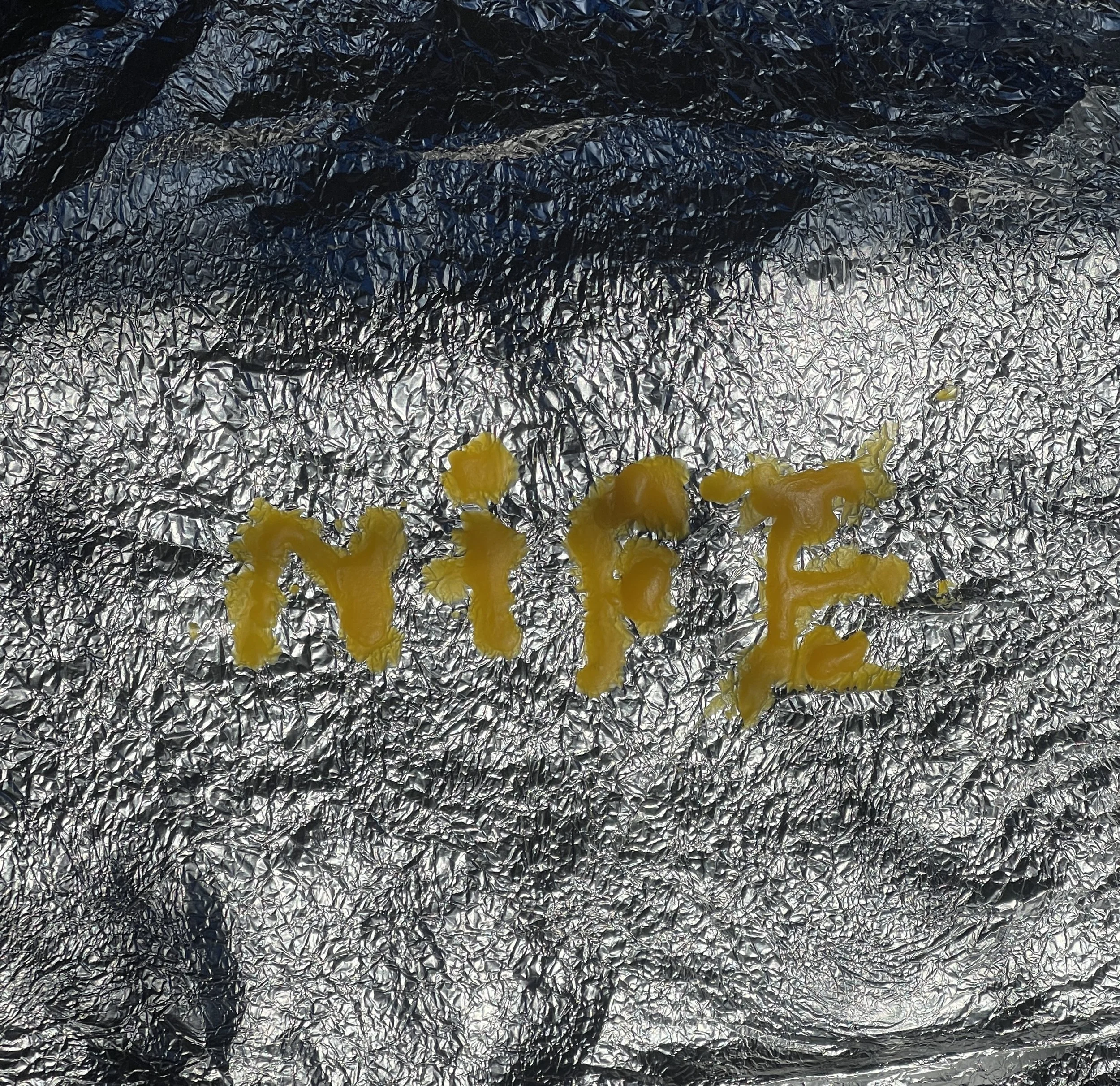 Word 'NIFE' written in mustard on aluminum foil background.