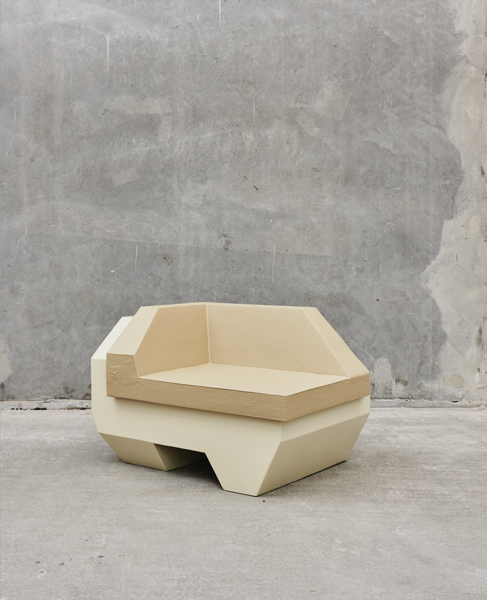 Modern beige armchair with geometric design against a textured gray wall