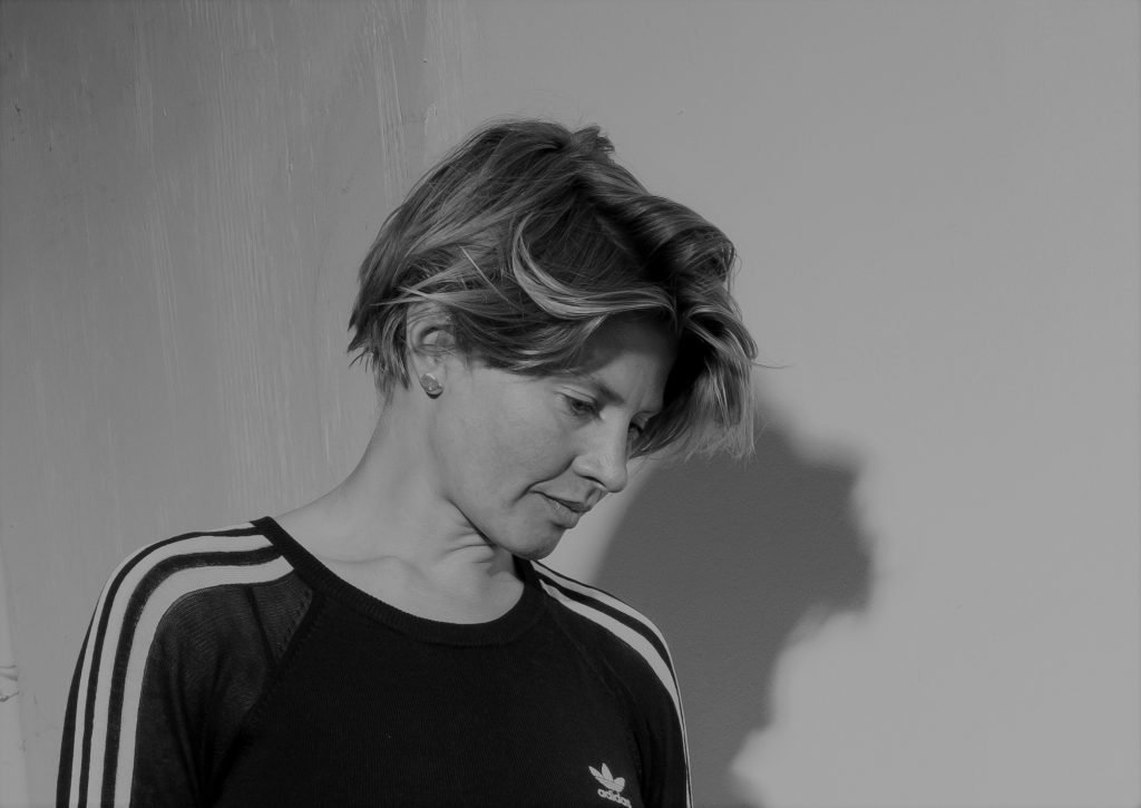 Black and white portrait of a person with short hair looking down, wearing a striped shirt.