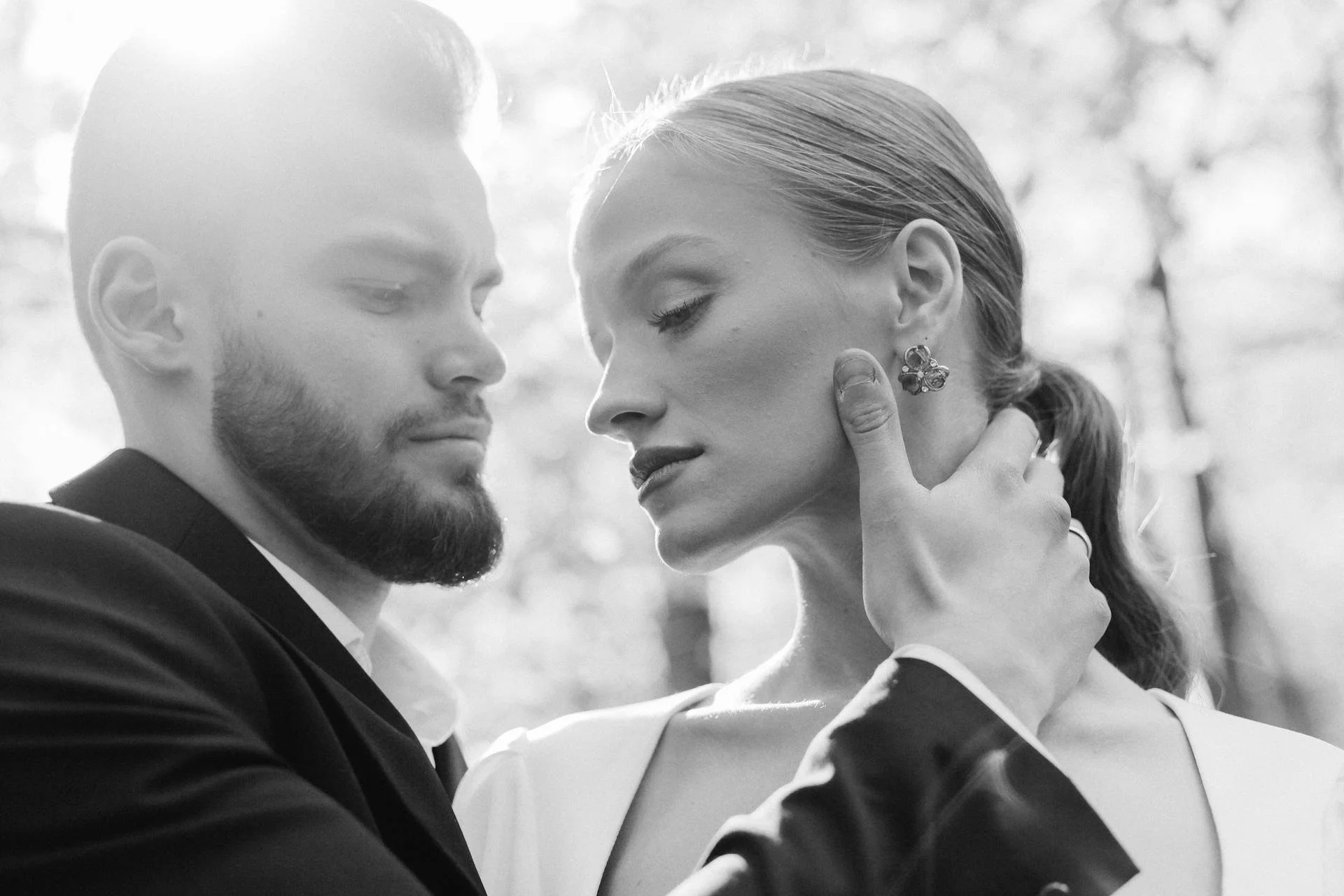 Wedding Website Design, Digital Wedding Stationery, Web Design and Branding for Wedding Professionals | Avelã White. Black and white photo of a man and woman in an intimate pose, with the man's hand gently touching the woman's face.
