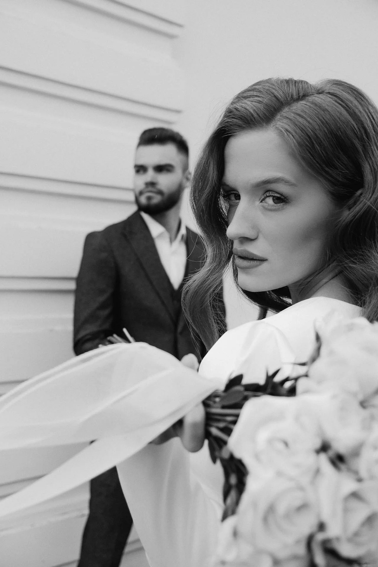 Wedding Website Design, Digital Wedding Stationery, Web Design and Branding for Wedding Professionals | Avelã White. Bride holding bouquet with groom in background, black and white photo.