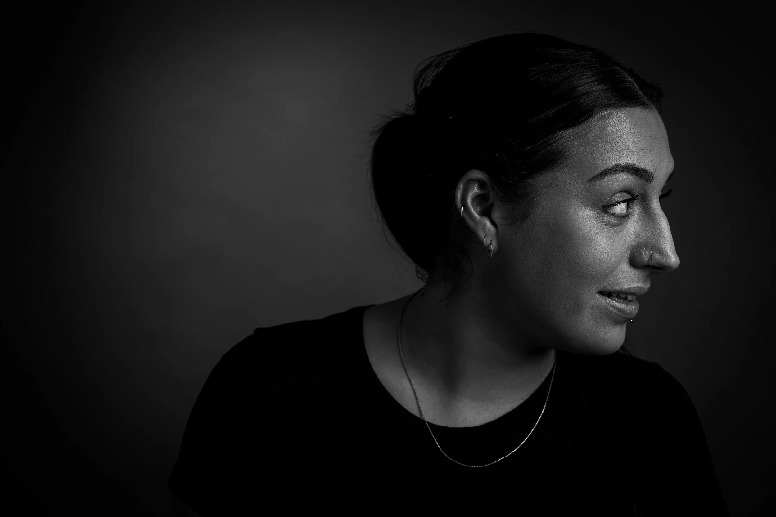 Black and white portrait of a woman with dark hair styled in an updo, looking to her right against a plain background.