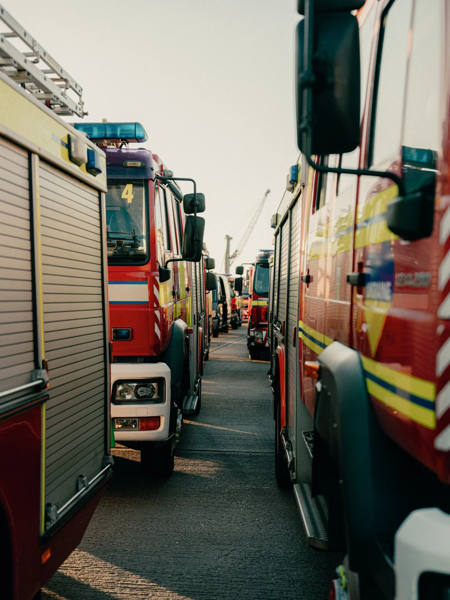 Line of fire trucks parked closely together on a street, viewed from between two trucks.