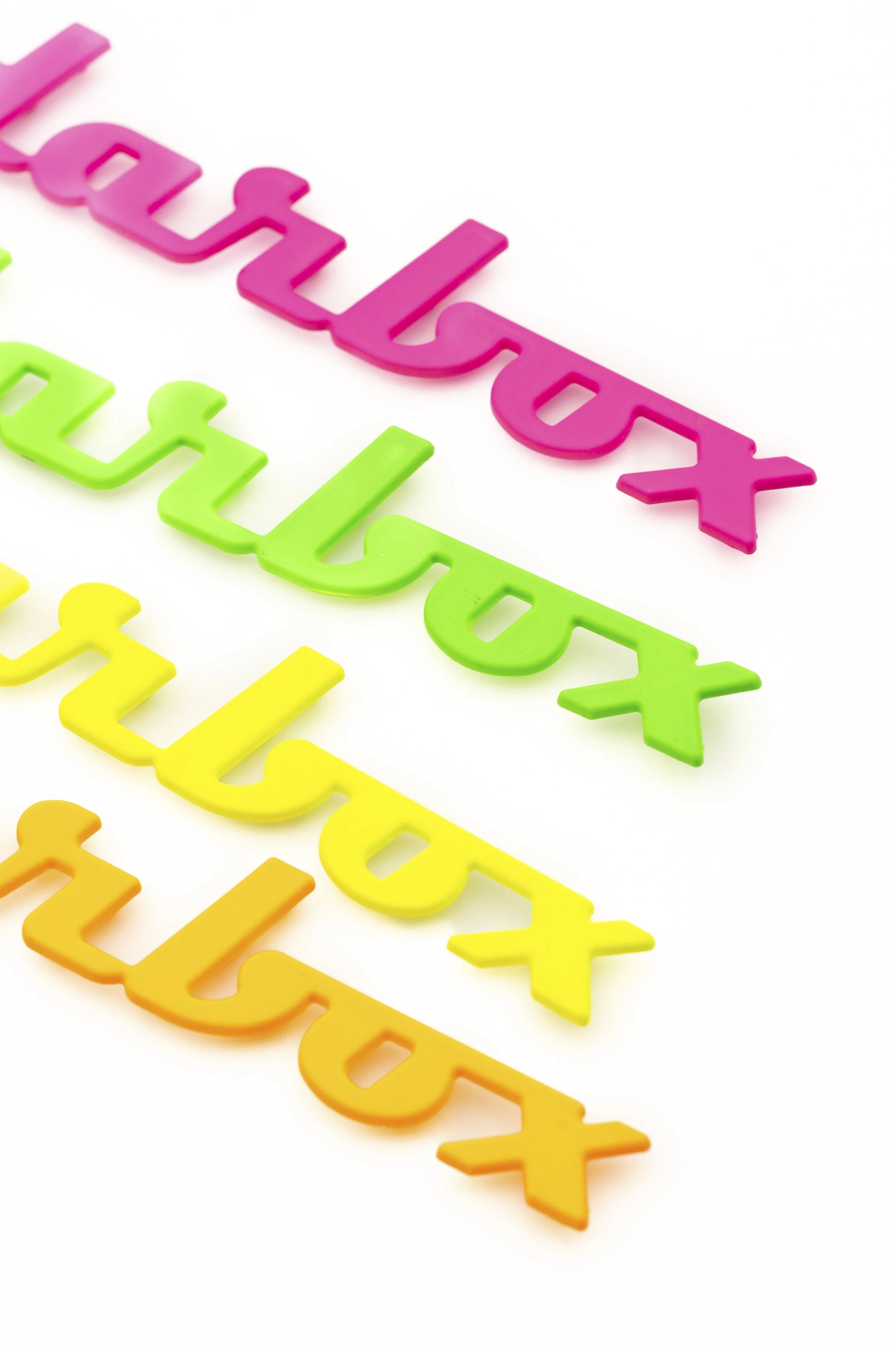 Letras de colores en forma de X en orden arcoíris, desde rosa hasta naranja, en fondo blanco.