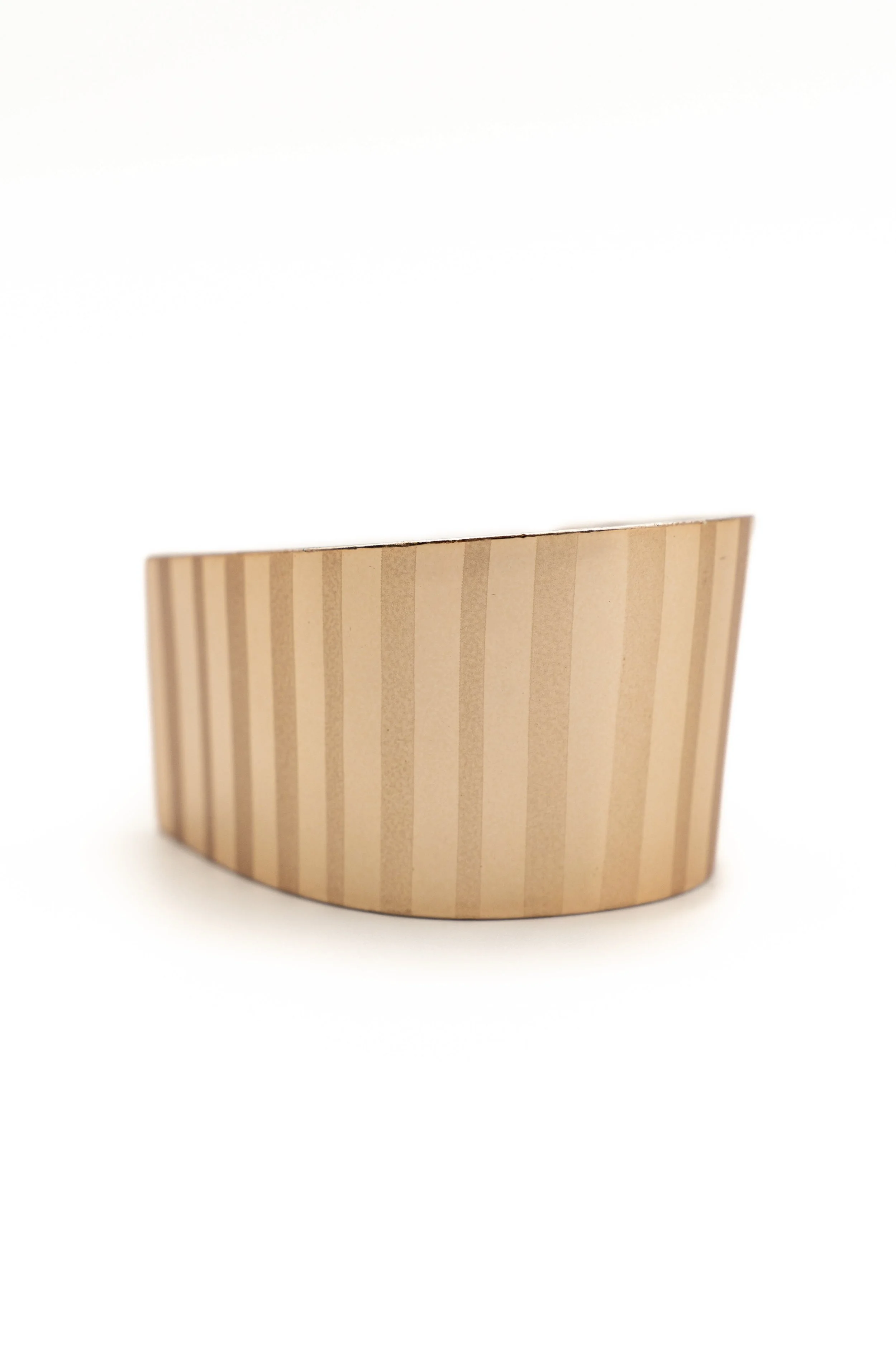 Un recipiente de madera en forma semi-circular con rayas verticales en diferentes tonos de marrón.