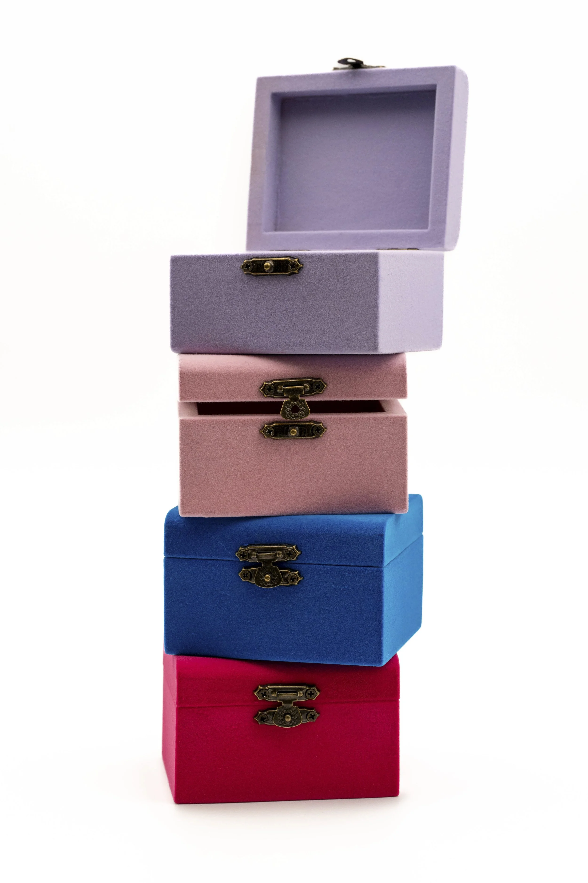 Una pila de cinco cajas apiladas de diferentes colores: azul, rosa, morado, y rojo, con cerraduras antiguas, sobre fondo blanco.
