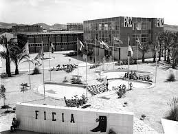 Imagen en blanco y negro de un campus universitario con edificios modernos, áreas verdes y una señal con la palabra 'FICIA'.