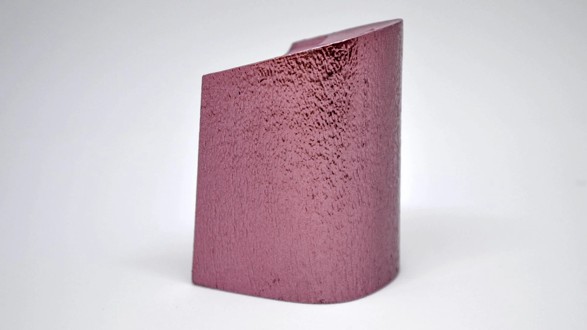 Ladrillo de color rosa con textura rugosa, de forma rectangular, colocado sobre fondo blanco.