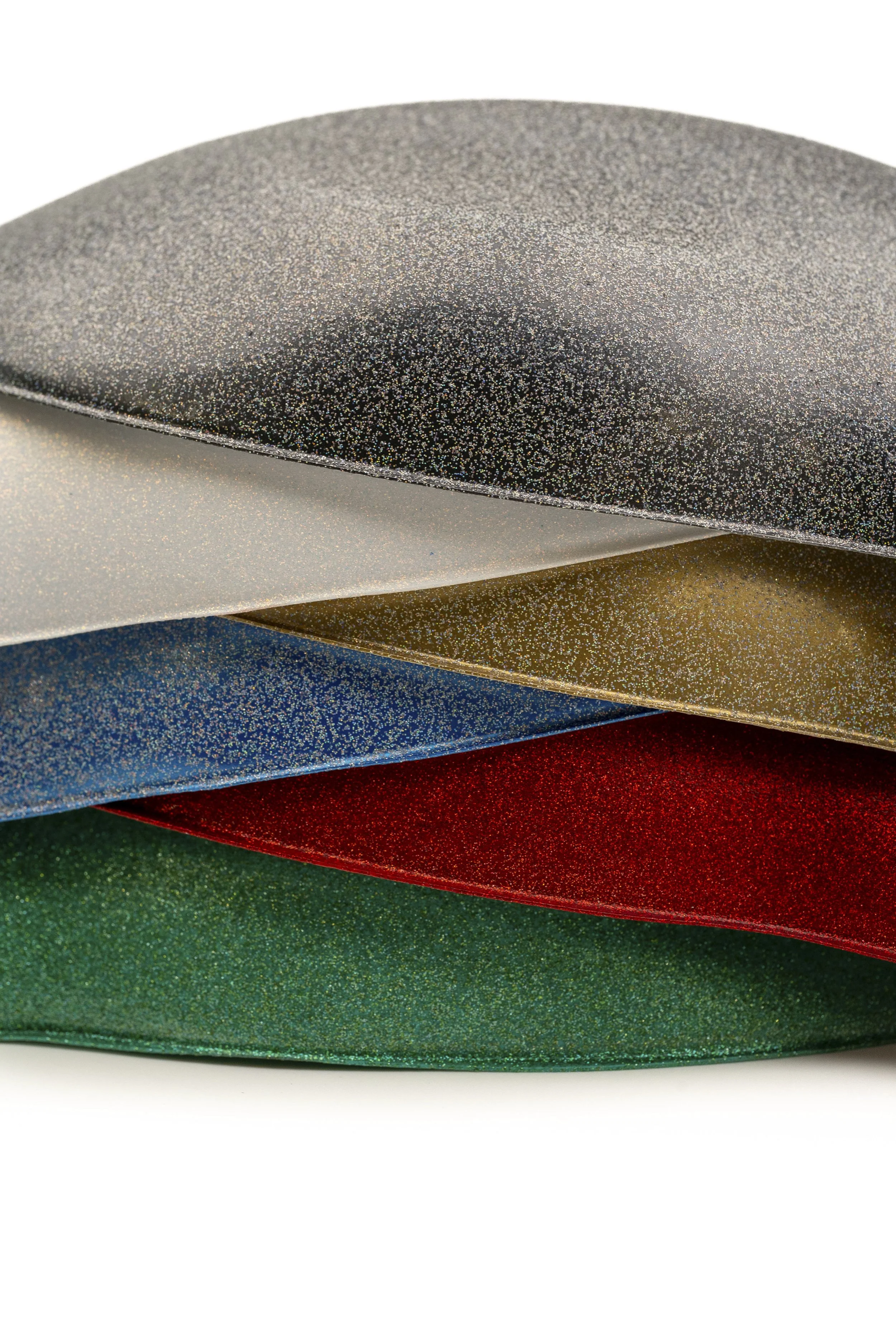 Seis hojas de papel de diferentes colores con una textura brillante y granulada apiladas horizontalmente, en tonos de gris, plata, dorado, azul, rojo y verde.