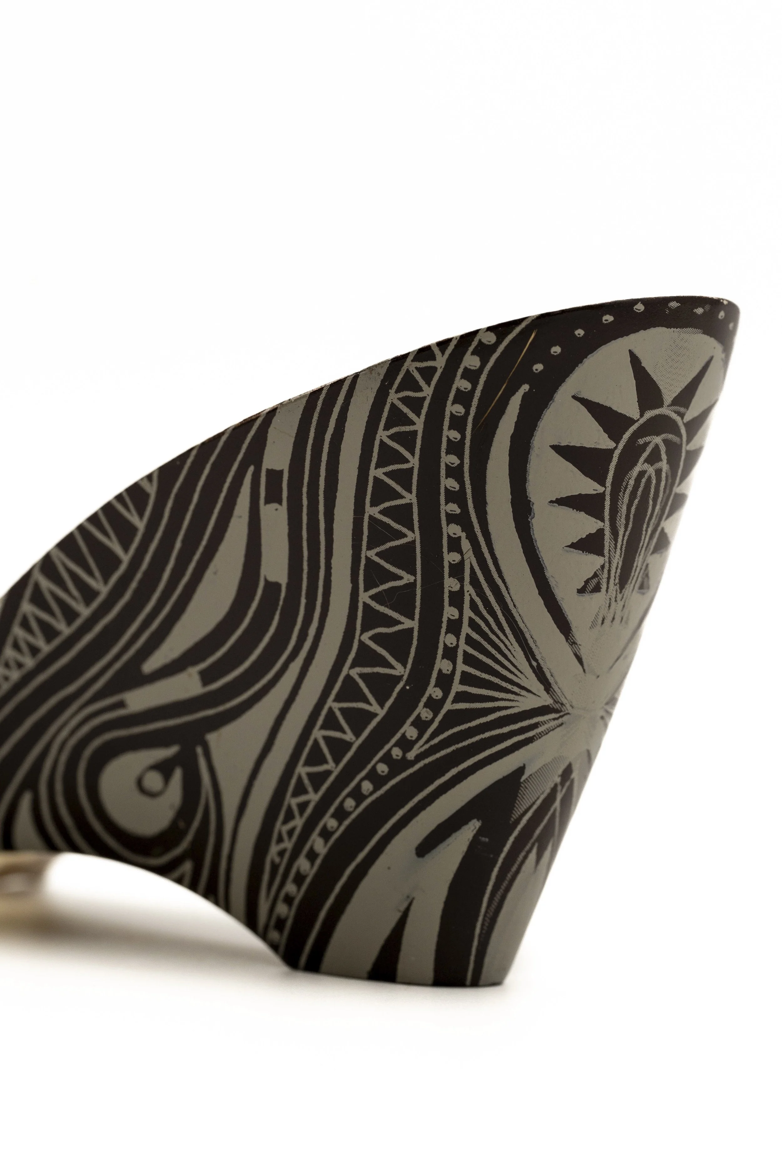 Vista lateral de un objeto decorativo con patrones en negro y blanco, con diseño tribal