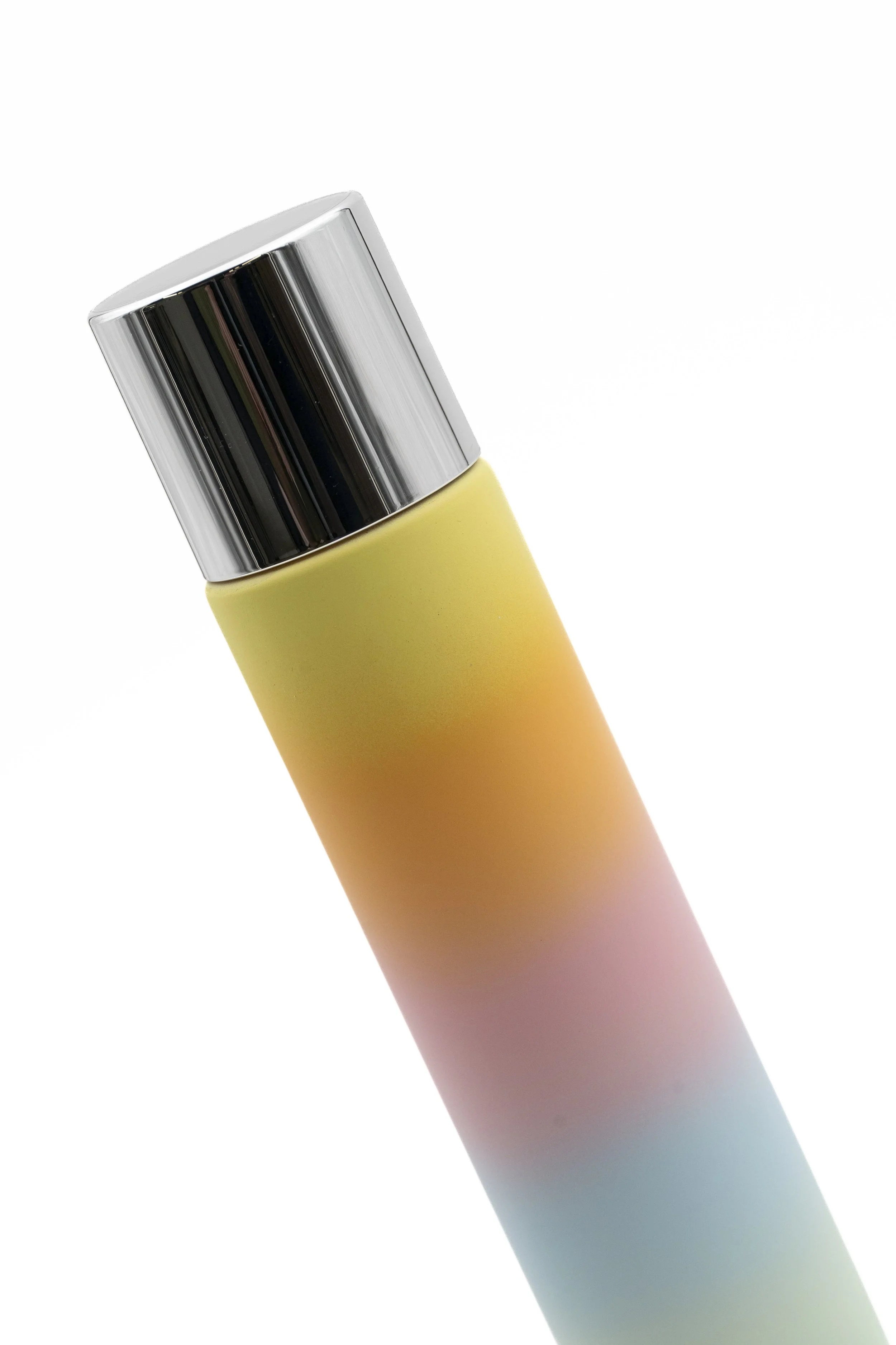Un envase de aerosol con un acabado metálico y una etiqueta con un degradado de colores pastel que va desde amarillo, rosa, verde hasta azul, colocado en un fondo blanco.