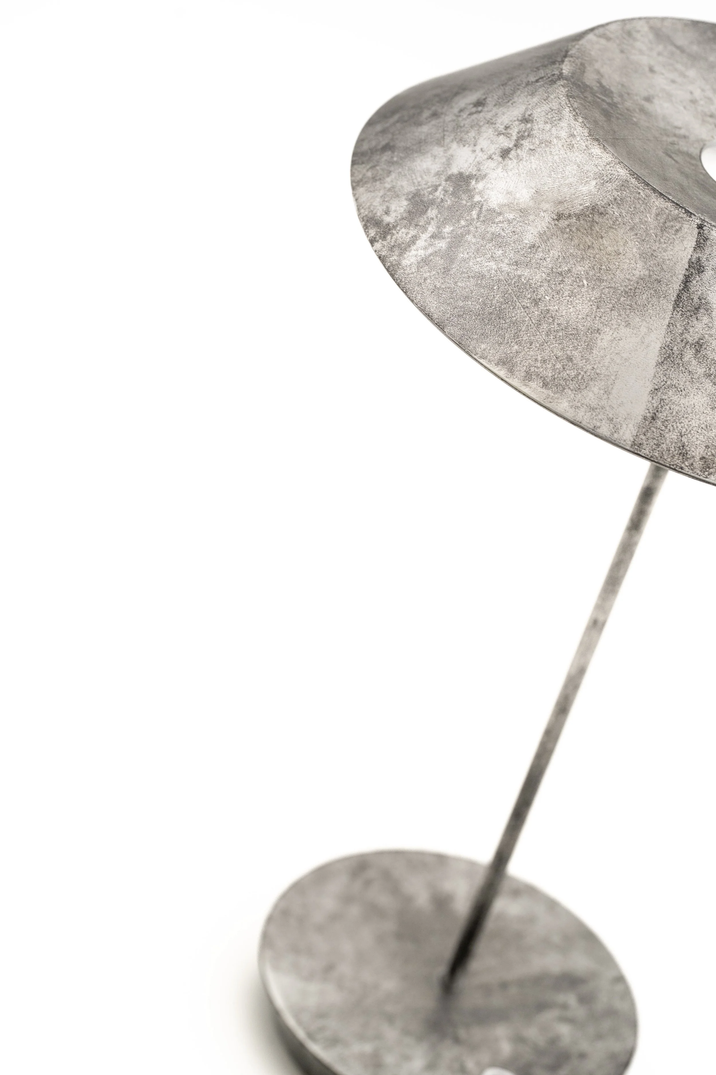 Una lámpara de mesa de estilo industrial con estructura de metal y base circular, en color gris, con dos niveles y una varilla vertical que soporta la luz.