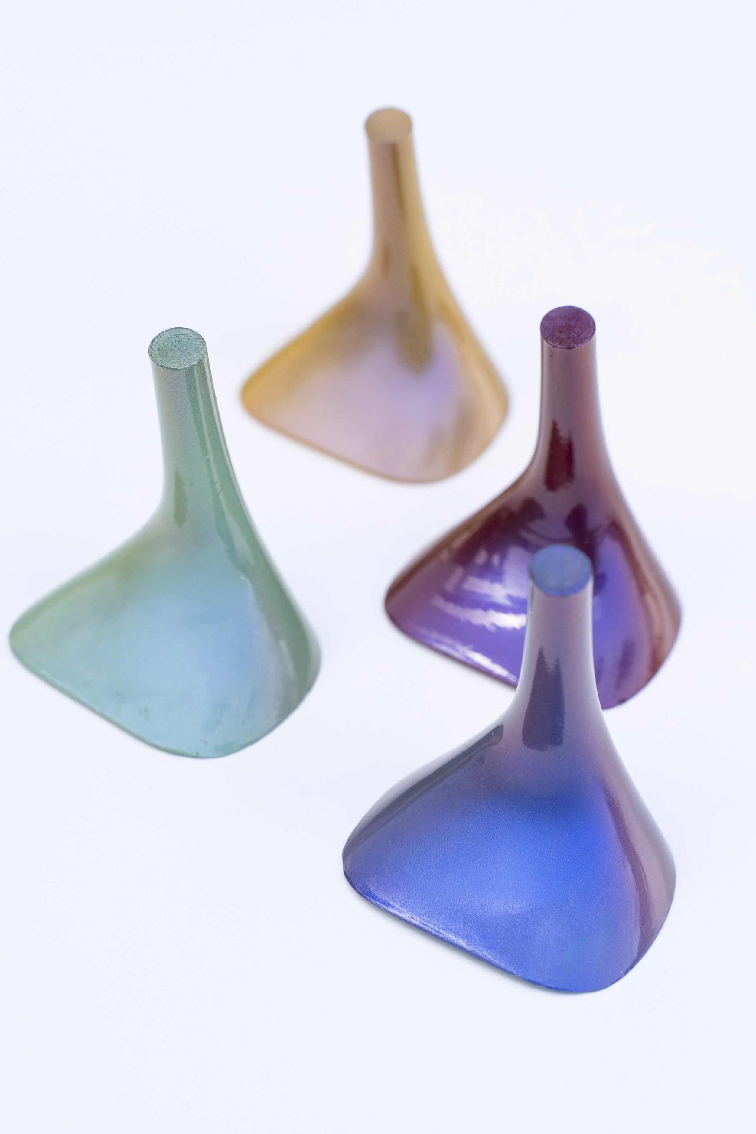 Tres frascos de vidrio de colores pastel, en tonos de azul, rosa y amarillo, vistos desde arriba sobre fondo blanco.