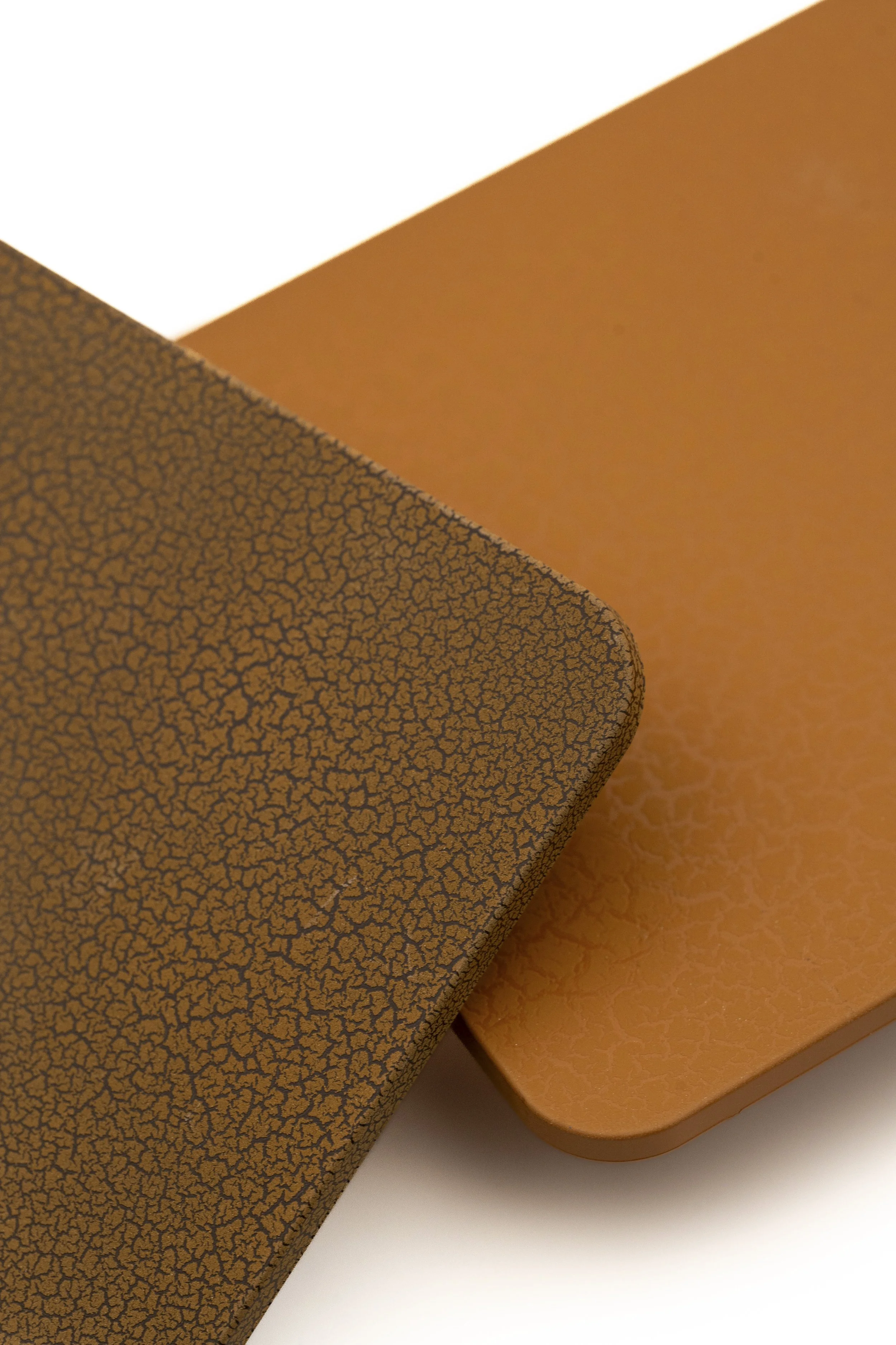 Primer plano de una estructura cuadrada con textura de patrón de grietas negras sobre fondo naranja. En el fondo, una superficie recta de color naranja clara y una parte blanca en la esquina superior izquierda.