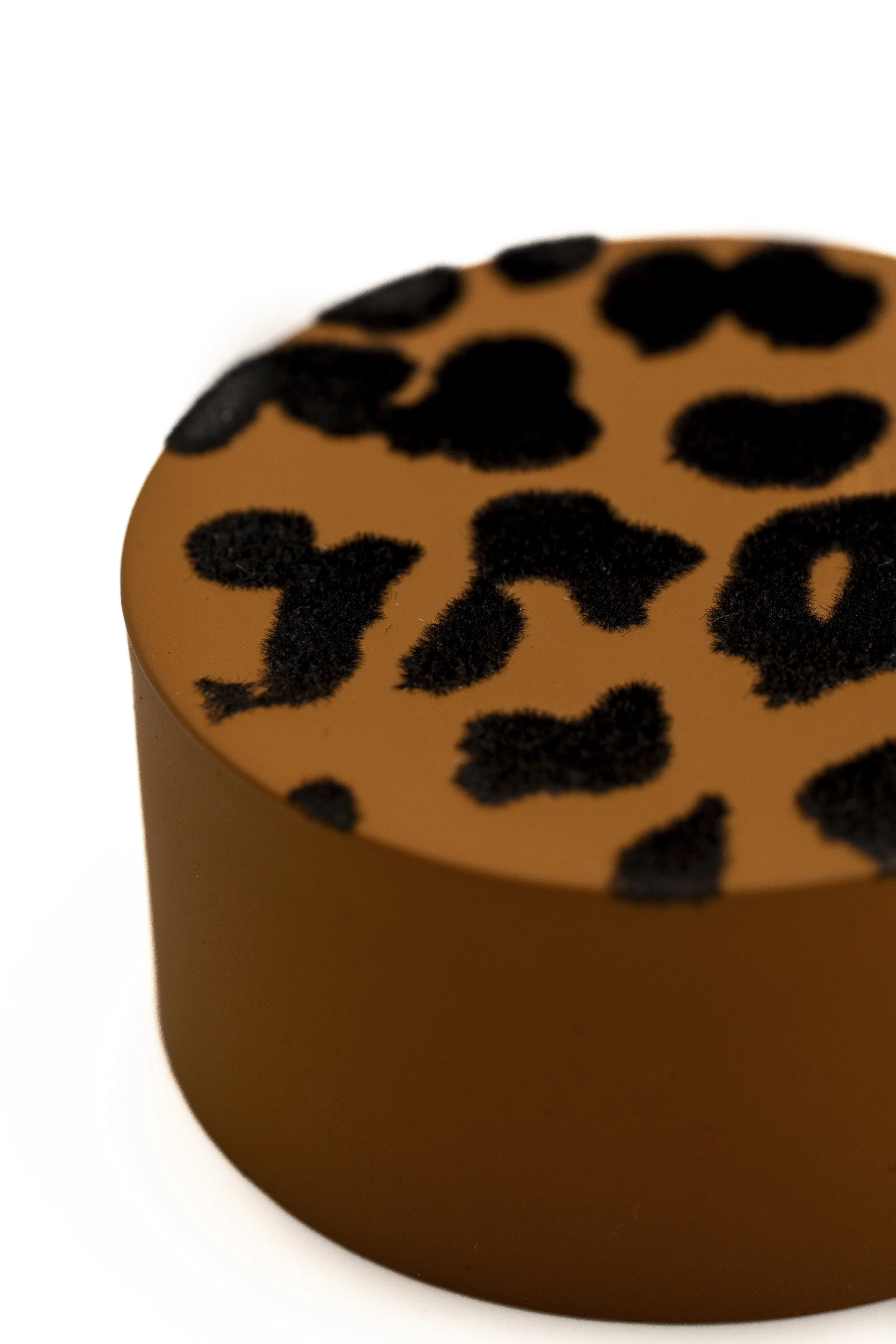 Figura de un recipiente con estampado de manchas negras en fondo beige.