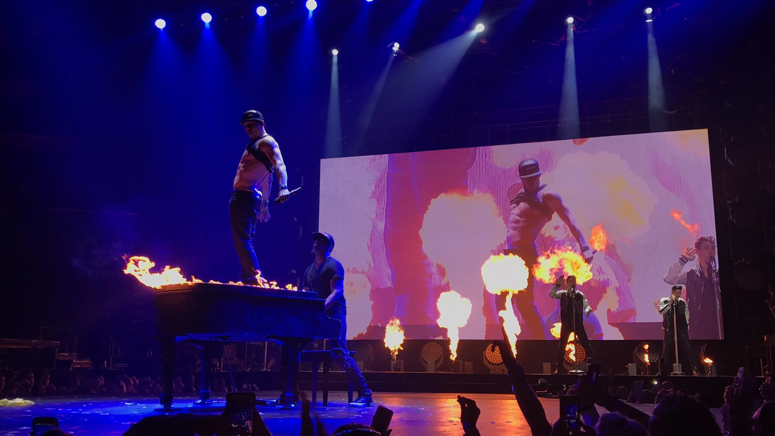 Rob Lewis performing on a flaming piano with New Kids On The Block during a live concert.