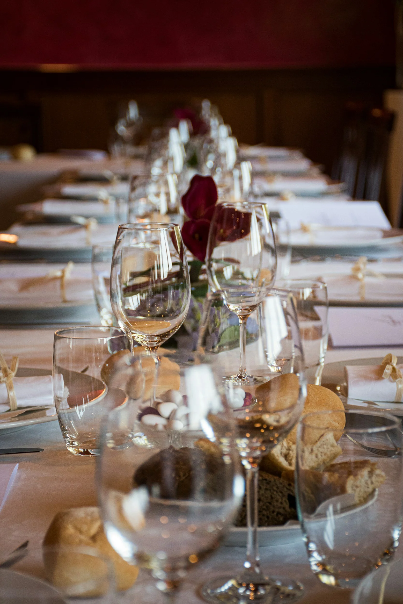 Ein schön gedeckter Tisch mit Gläsern, Tellern und einer kleinen Blumenmitte, möglicherweise für eine formelle Veranstaltung oder ein Abendessen.