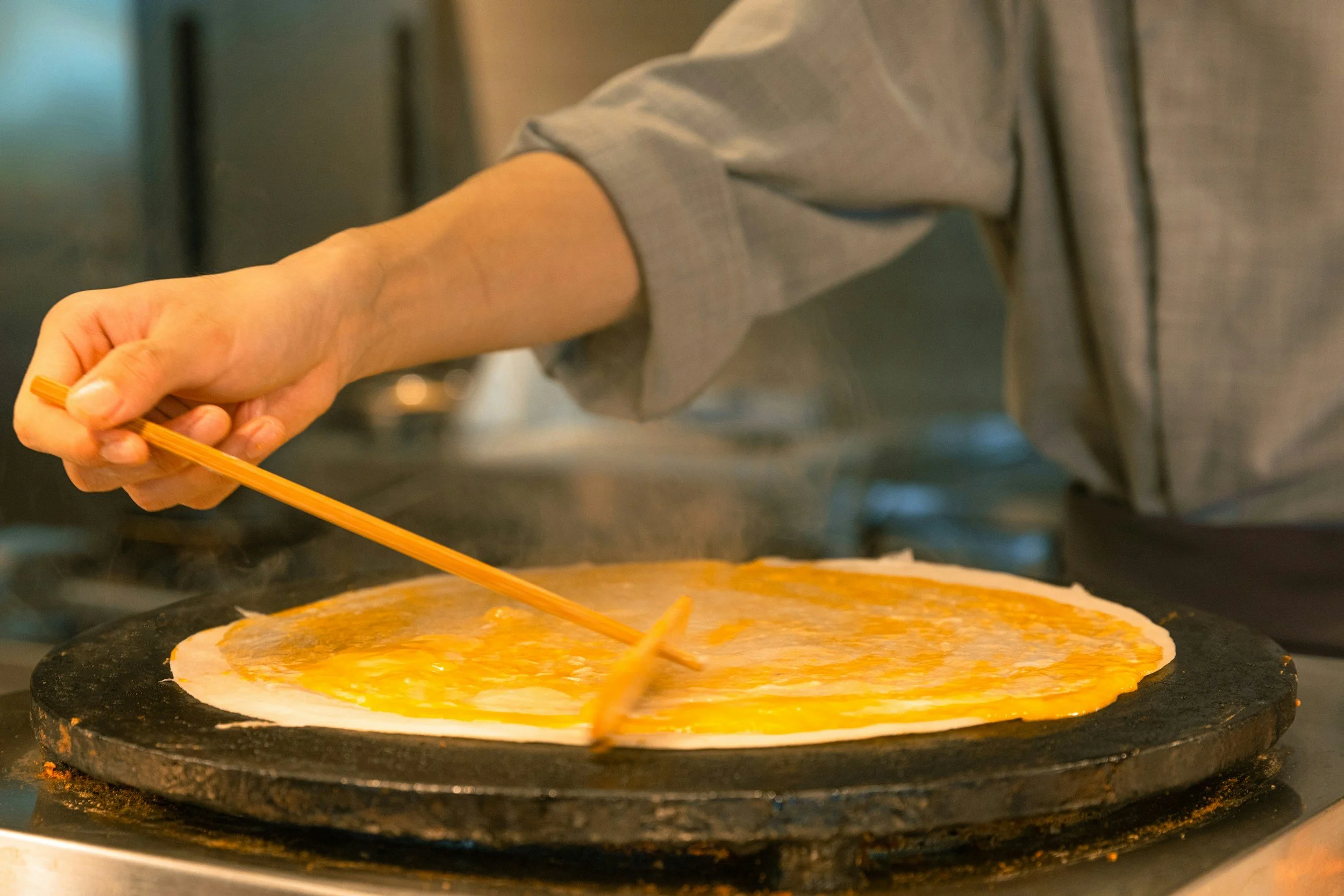 Eine Person bereitet eine Pizza mit Käse auf einem heißen Stein im Ofen zu.