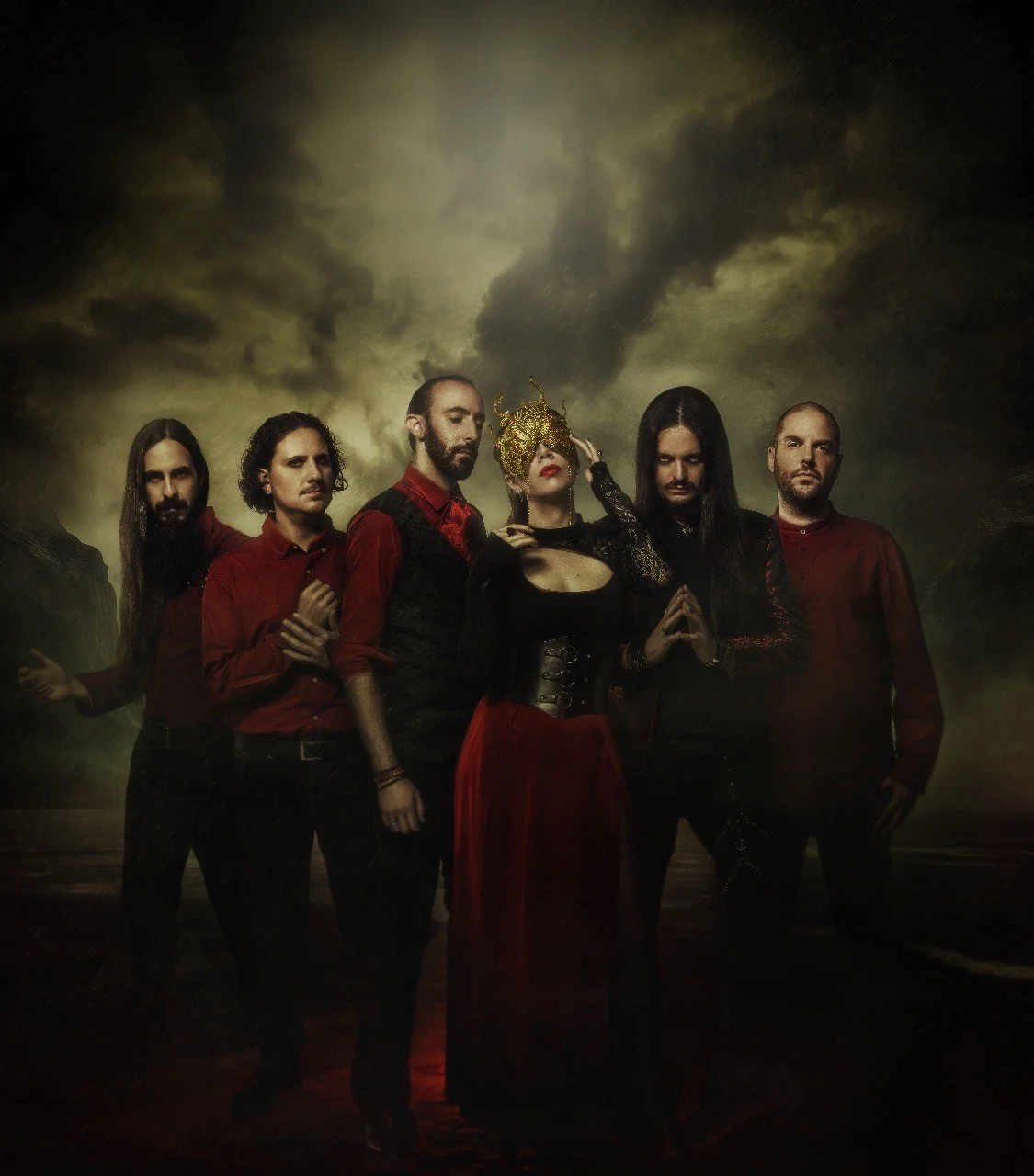 Group of six people dressed in dark, gothic style clothing standing in front of a dark, stormy sky.