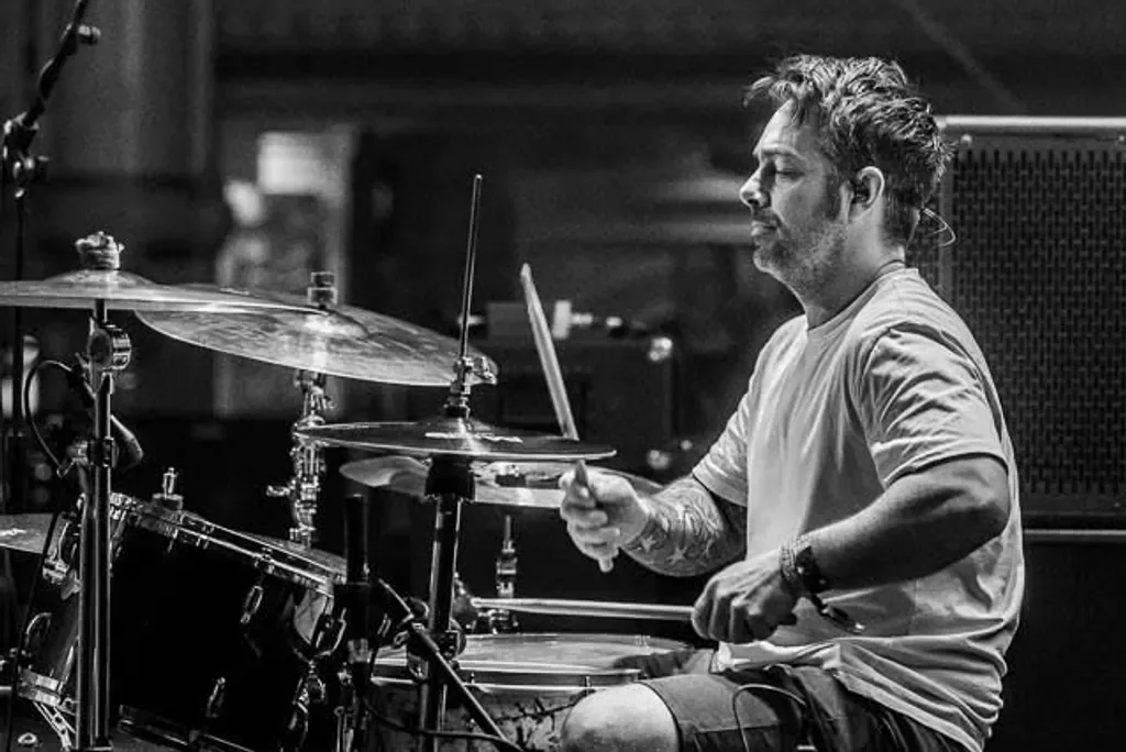 A man playing a drum set in a recording studio.