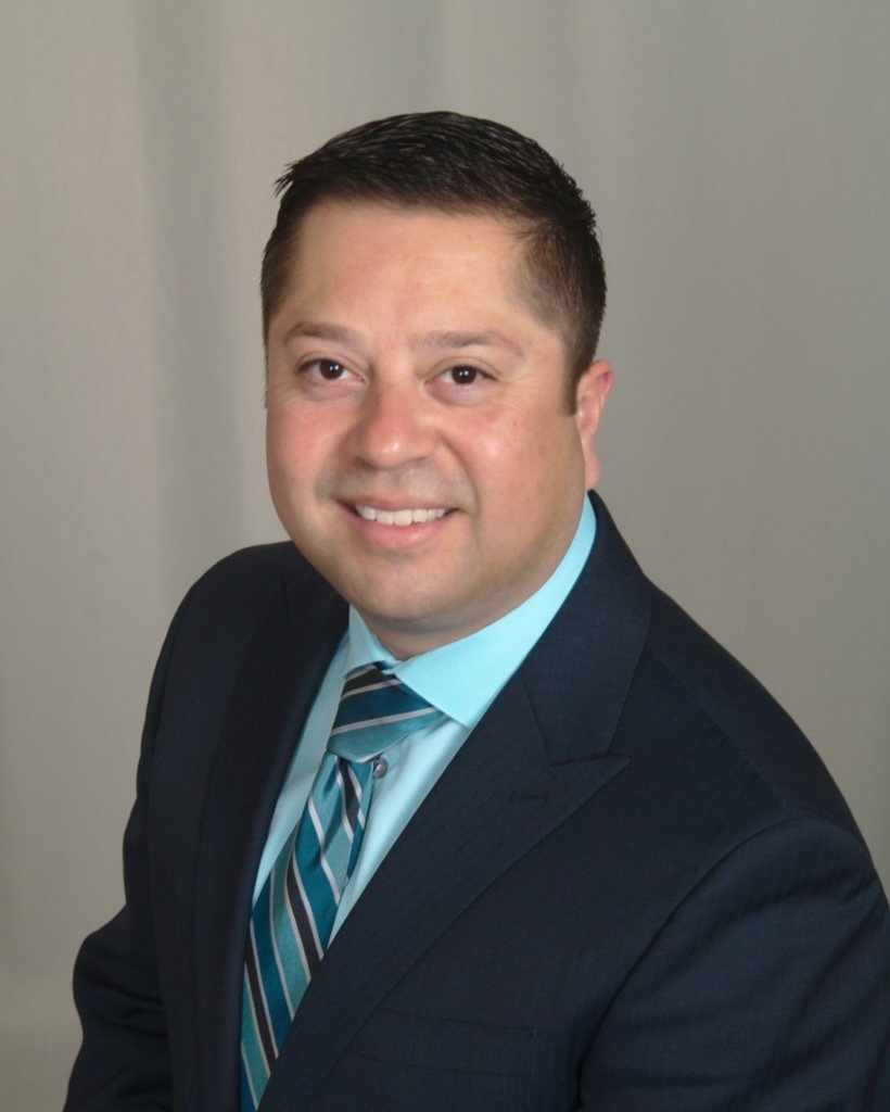 Woman sitting on a bench, writing in a notebook, in a room with a wooden wall and abstract art on the floor.