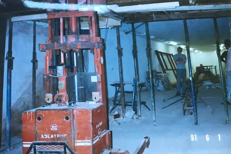 Construction workers and scaffolding inside a building under renovation, with a red construction lift in the foreground. K G Croft archive images.