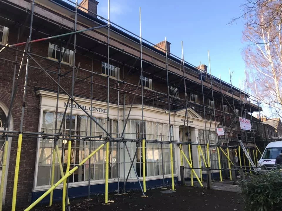 A building labeled 'Medical Centre' in north london under renovation with scaffolding surrounding it. Works by K G Croft.