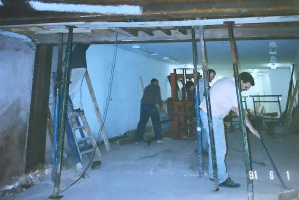 Workers installing or repairing a ceiling in a room with construction equipment and scaffolding. K G Croft archive images.