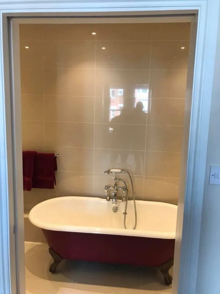 A vintage-style bathtub with clawfoot legs in a bathroom with beige tiled walls.