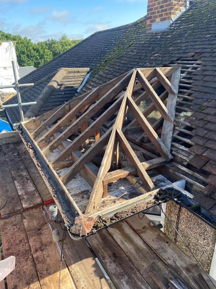 Roof undergoing repairs by K G Croft in north london with new wooden rafters installed and old shingles removed, revealing the roof structure. 