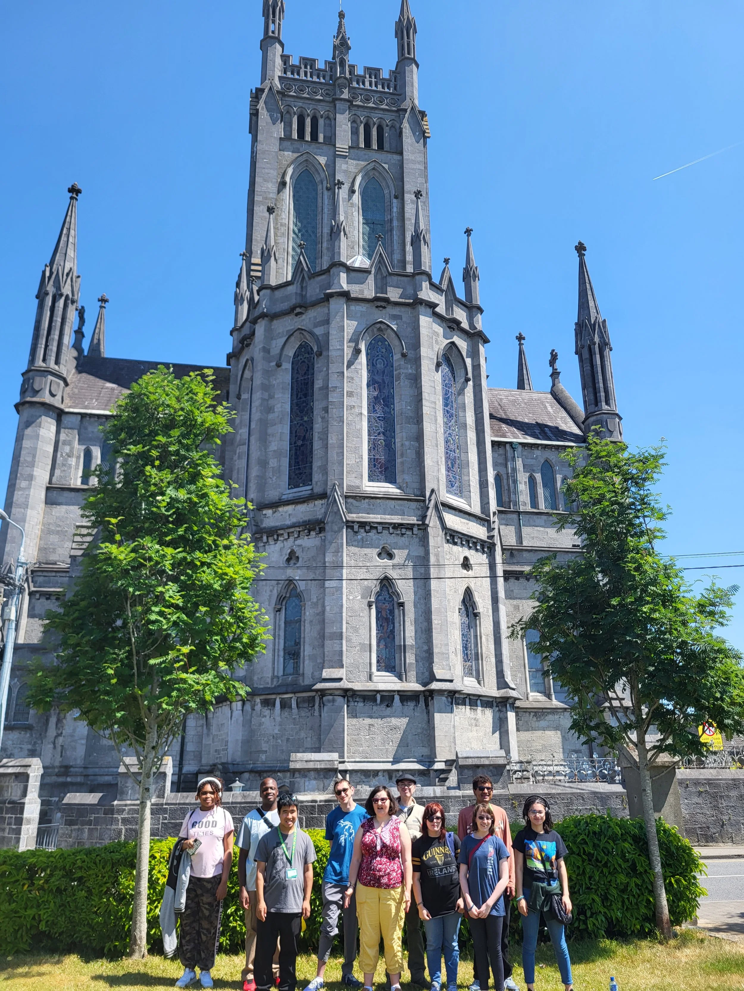 Group of 10 smiles at the camera in front of a church in Ireland