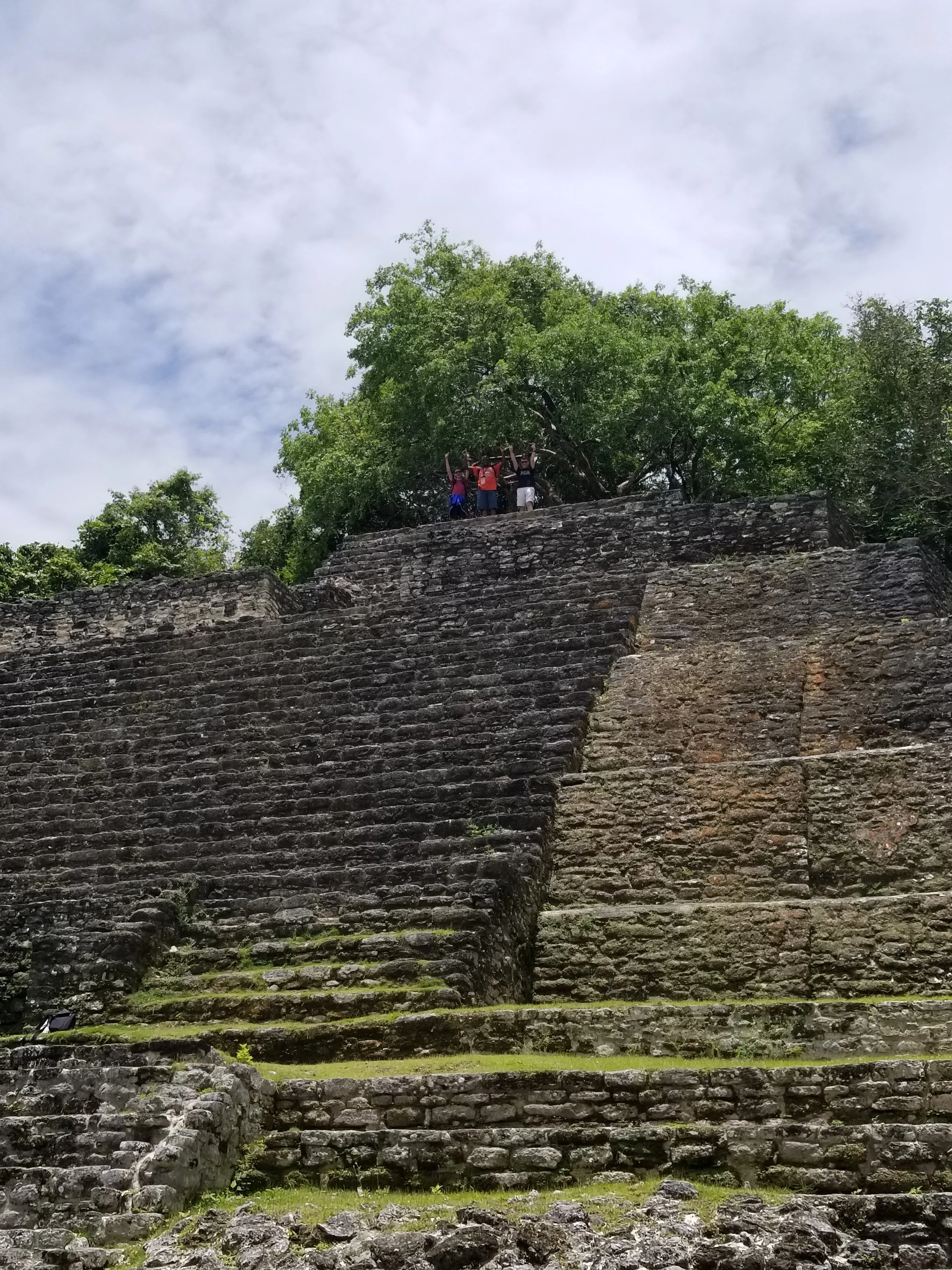 On top of the world!-  2022 - Travelers were permitted to climb to the top of this pyramid in Lamani (you can't do this anymore). The pictures shows the large pyramid structure with three of our travelers at the top, hands up in the air, waving to th