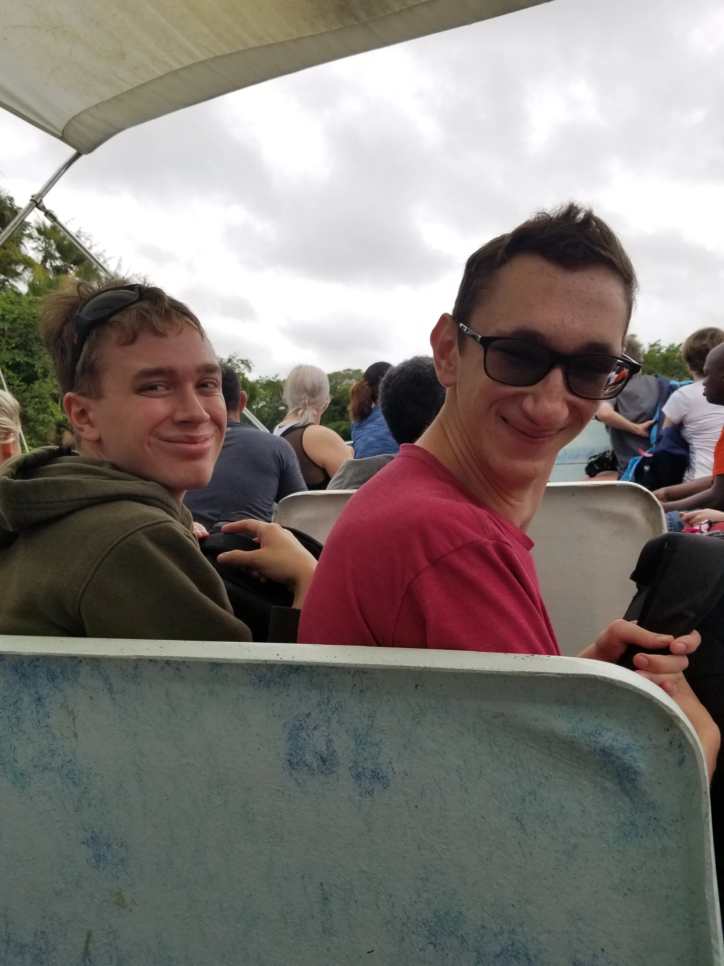 Two me are turned around, looking behind them toward the camera. They are on a boat ride to Lamani