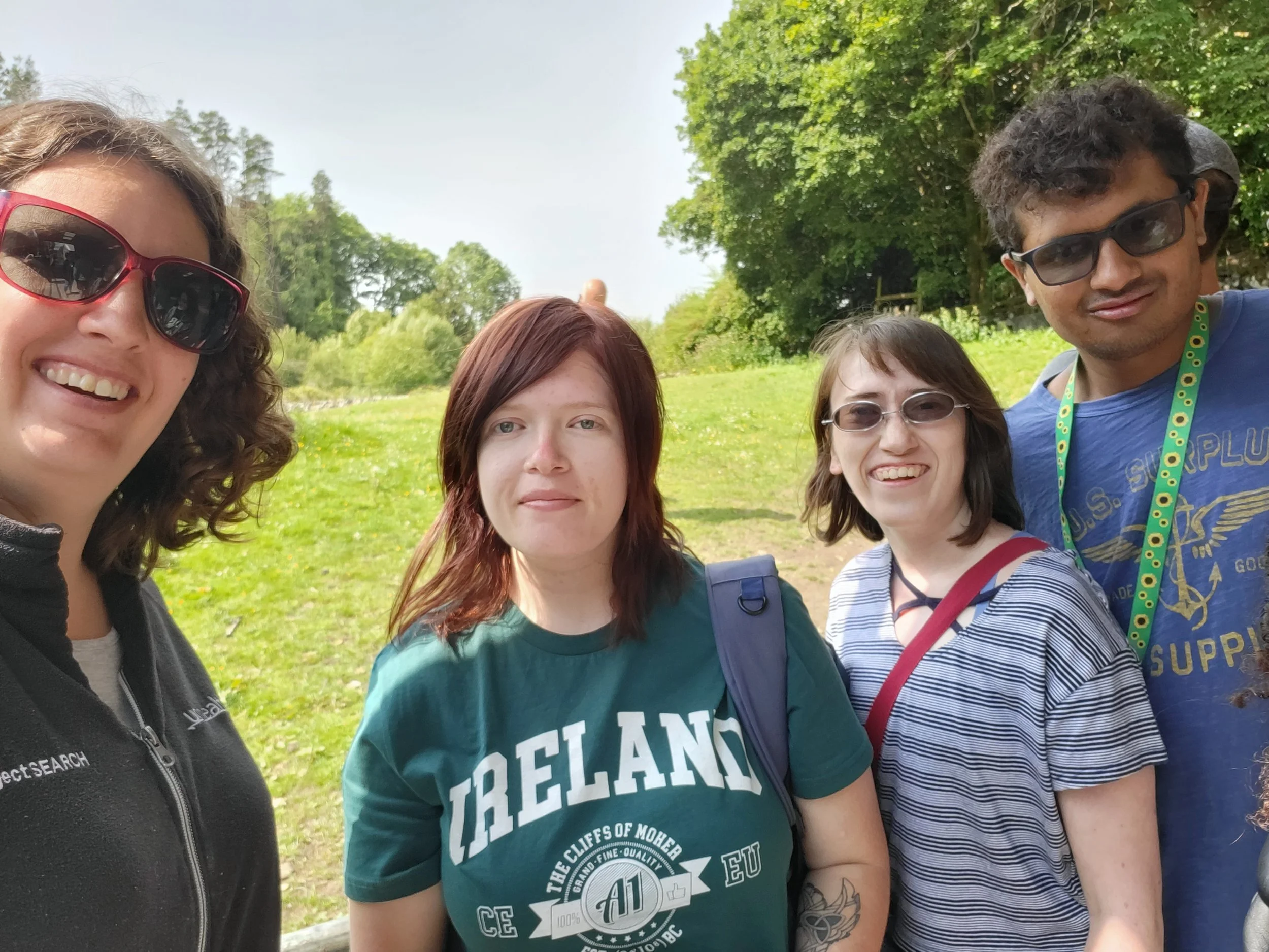 A group of four stand together in a sheep farm in Ireland.