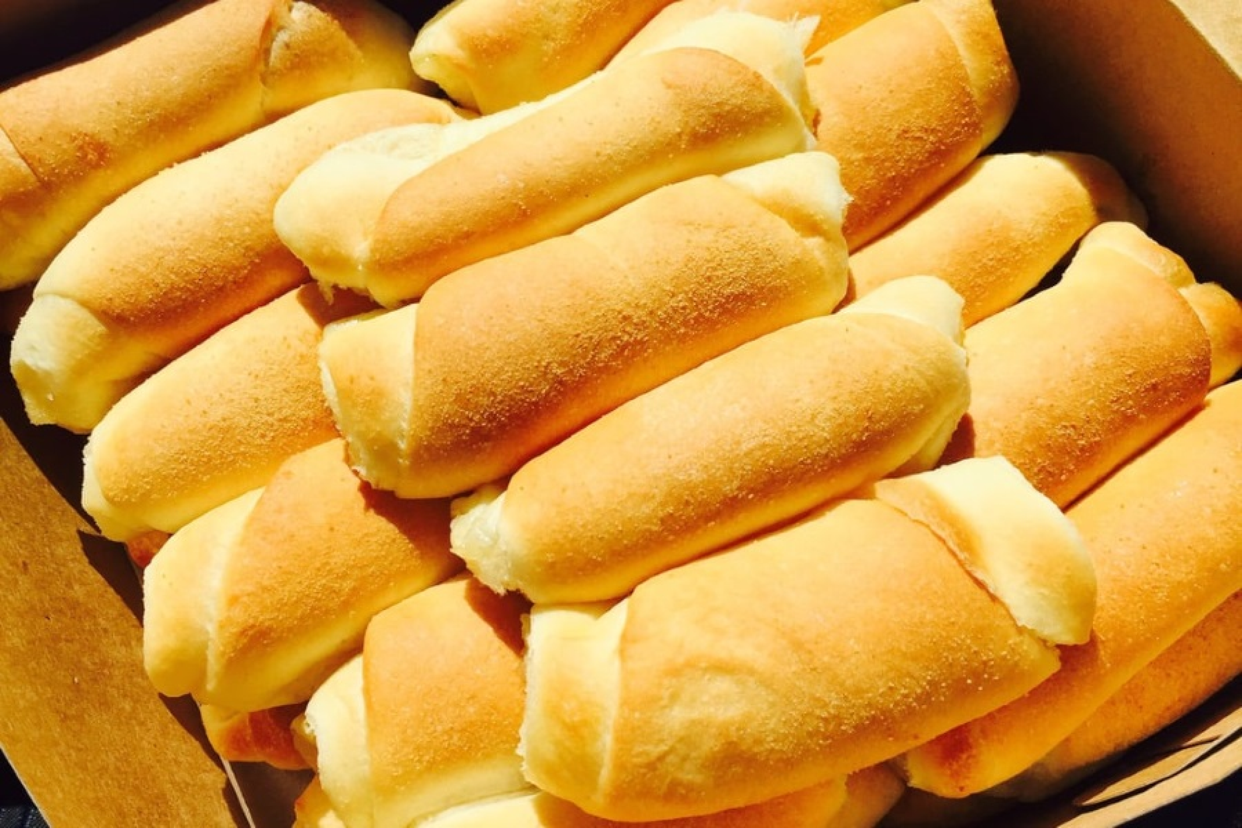 Close-up of several freshly baked bread rolls with a golden-brown crust, arranged in a basket.