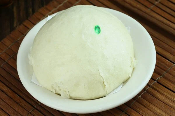 Dough ball on small white plate with a green dot on top