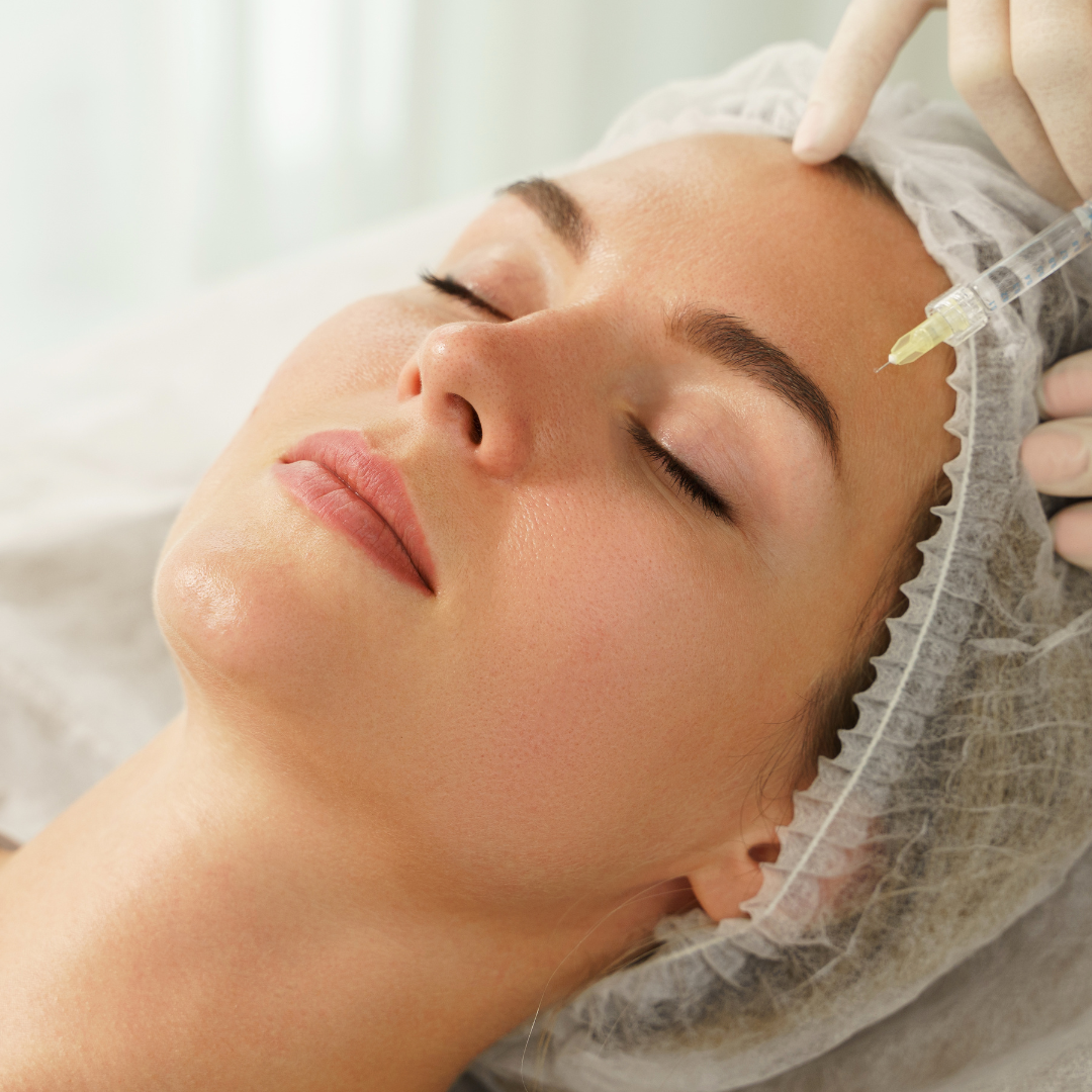 Woman receiving a facial treatment with a syringe near her forehead in a clinical setting. Genesis Skin Rejuvenation | Med Spa in AZ