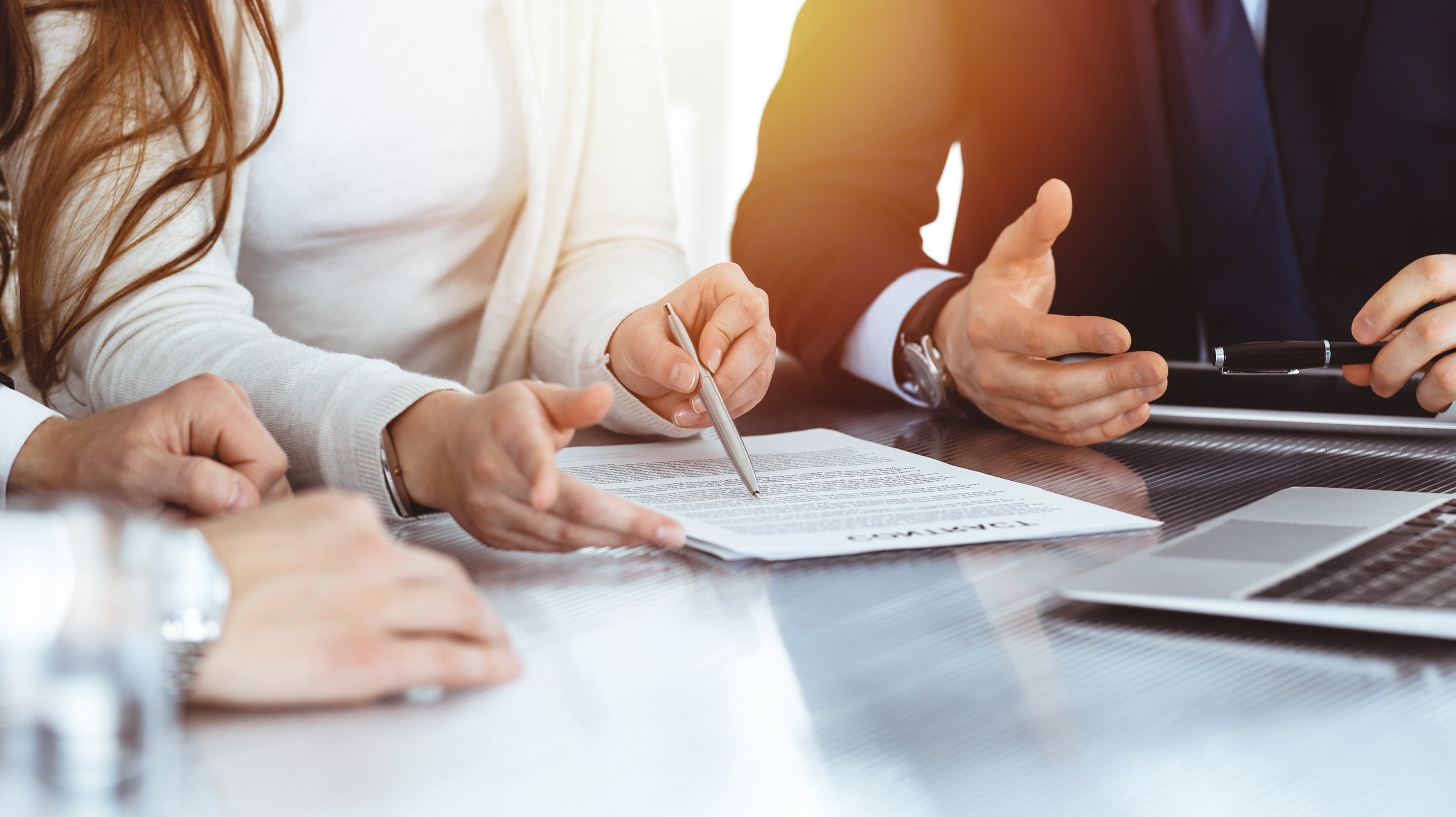 People sitting at a table during a business meeting, discussing a contract.