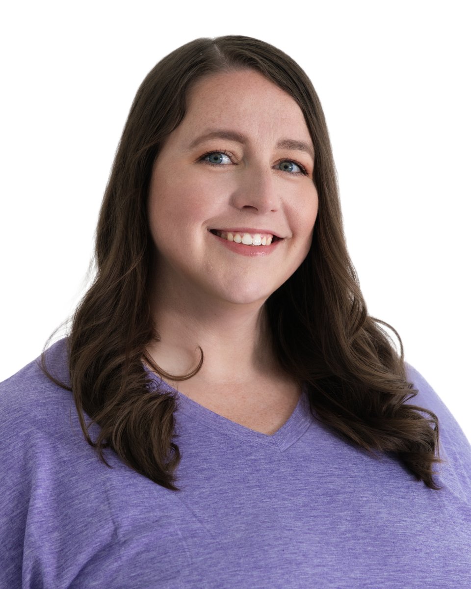 Portrait of a woman with long brown hair, blue eyes, smiling, wearing a purple top, against a white background.