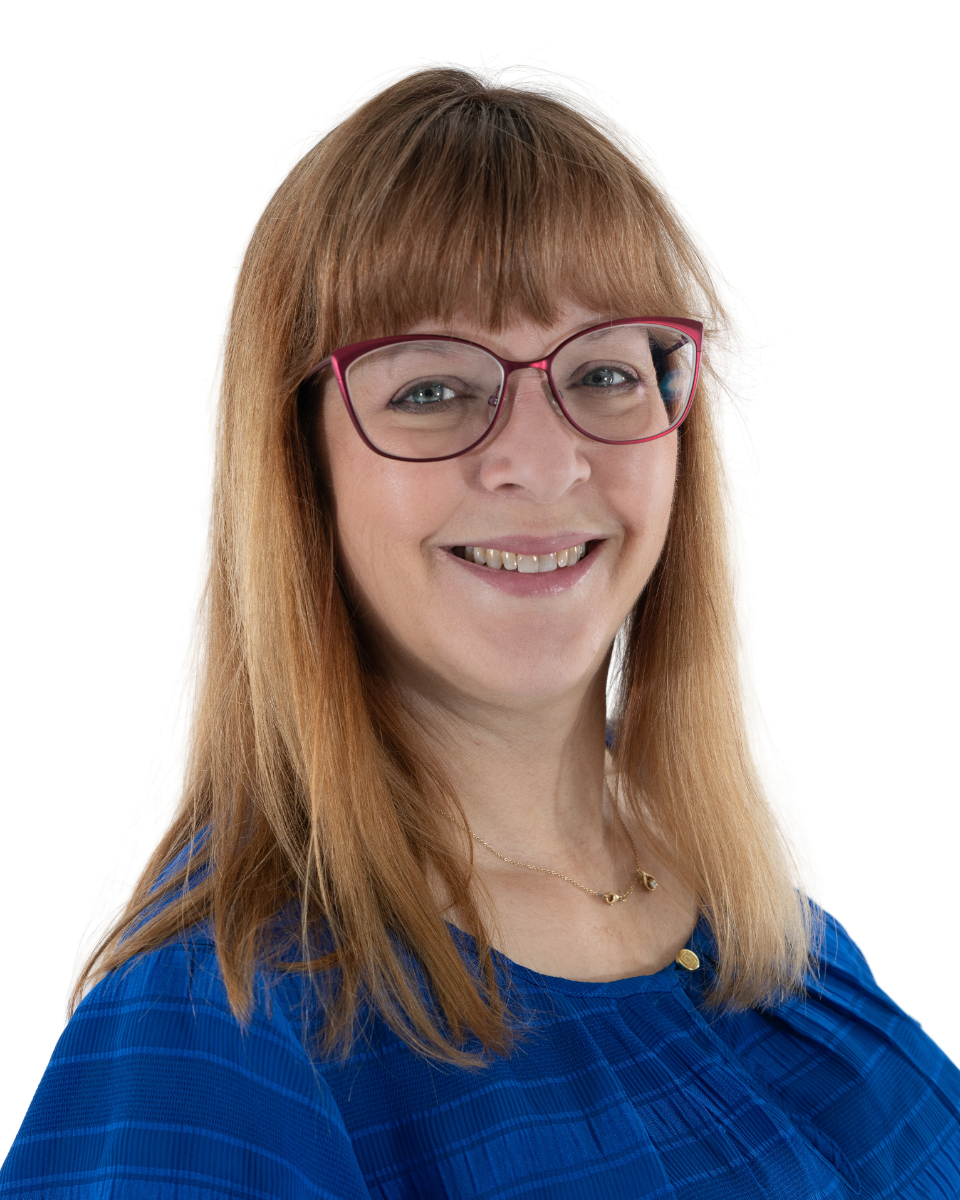Portrait of a smiling woman with red hair, wearing glasses and a blue top, against a white background.
