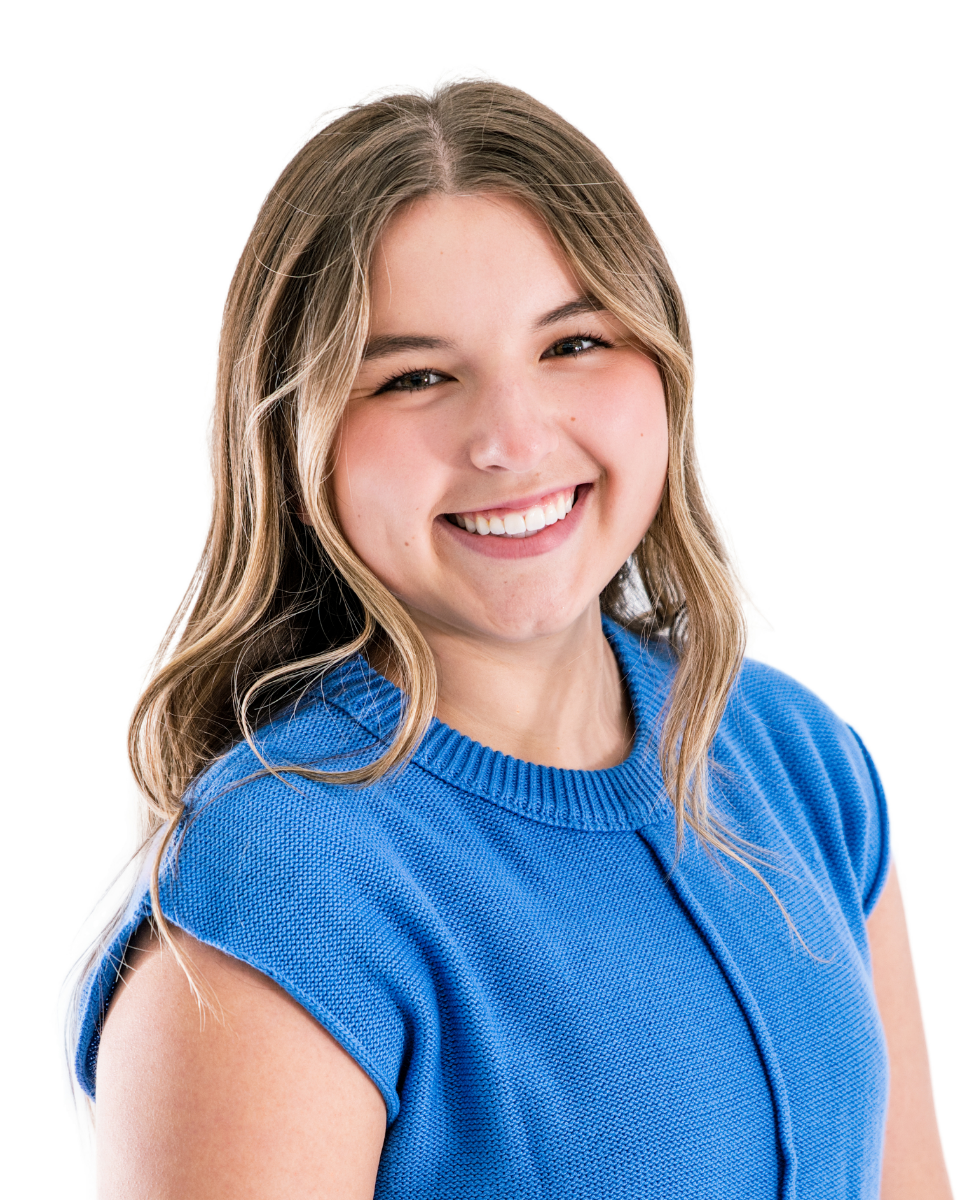 A young woman with blonde hair and fair skin smiling, wearing a blue sleeveless sweater, against a white background.
