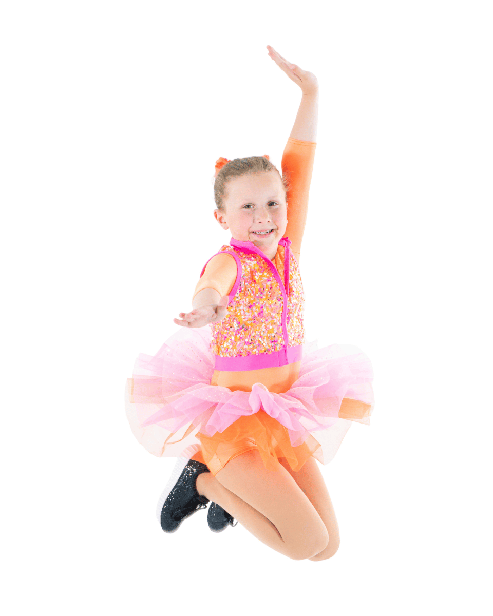 A young girl in a colorful dance costume jumping in the air with one arm raised, smiling, against a white background.