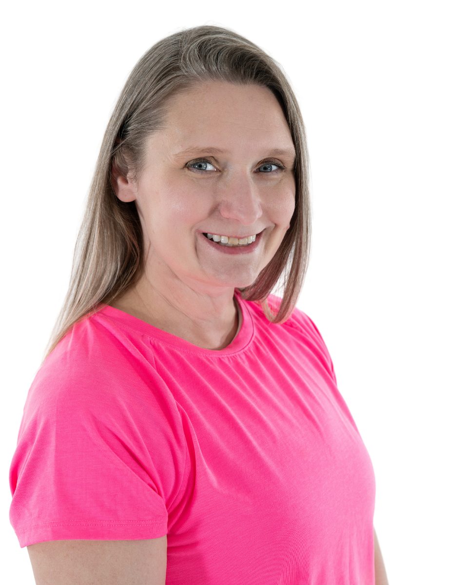 A woman with light brown hair and blue eyes wearing a pink T-shirt, smiling at the camera against a white background.