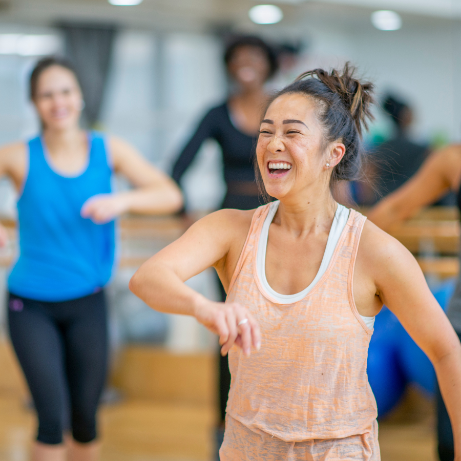 Women smiling and laughing during a fitness class in a gym