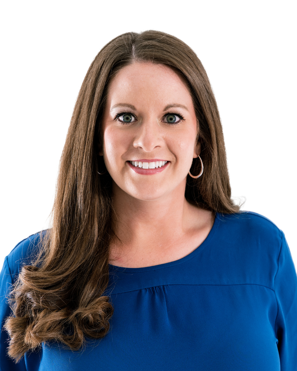 A smiling woman with long brown hair, green eyes, wearing a blue top and hoop earrings, against a white background.